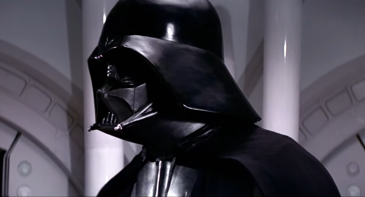 Darth Vader in a black suit and mask in a room with a futuristic silver design