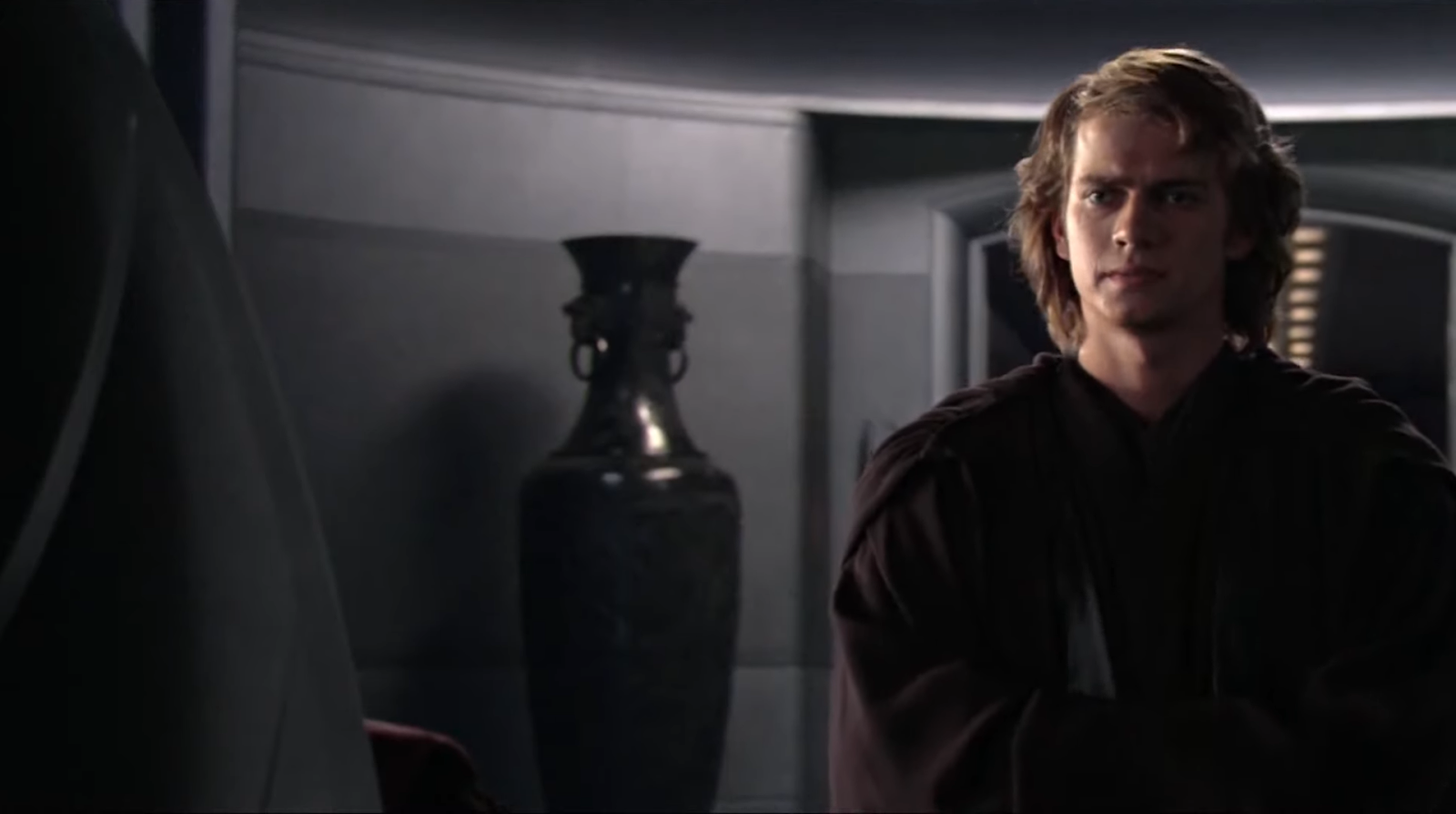 Anakin in coat standing in a room with bag vase in semidarkness