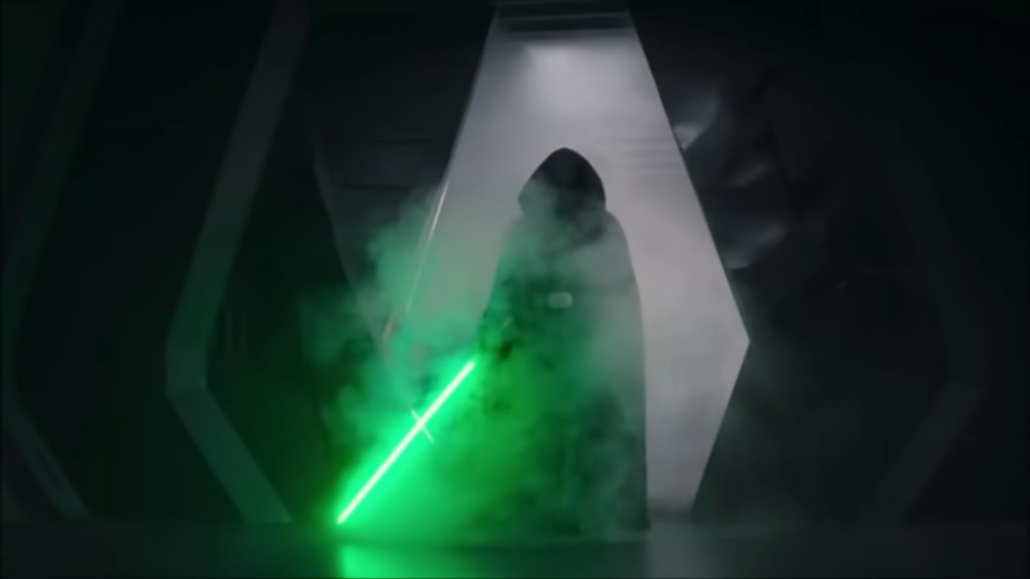 character in black hood with green sword standing in darkness surrounded by mist